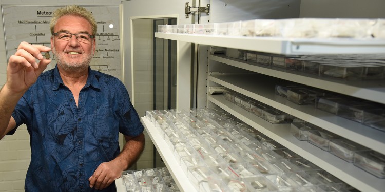 Ein ganz besonderes Sammlungsstück: Zwischen seinen Fingern hält Prof. Dr. Addi Bischoff den Meteoriten, in dem das nach ihm benannte neue Mineral „Addibischoffit“ entdeckt wurde.<address>© WWU - Peter Grewer</address>