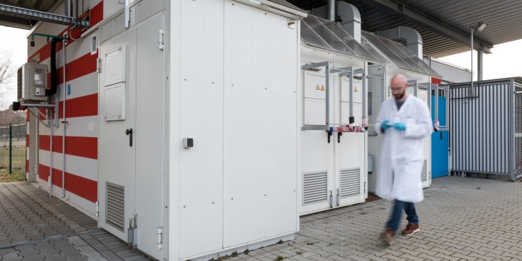 Die Wissenschaftler legen die Batteriezellen von außerhalb des Gebäudes in die Testkammern.<address>© WWU - Peter Leßmann</address>