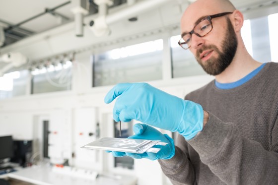 Dr. Markus Börner demonstrates outside the test rooms how a nail is drilled into a battery cell.<address>© WWU - Peter Leßmann</address>