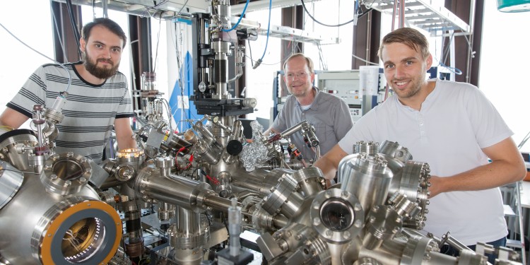 Four chambers and 19 pumps: MA student Fabian Schöttke (from left), Prof. Dr. Markus Donath and PhD student Philipp Eickholt use the vacuum machine to investigate phenomena based on spin, the intrinsic angular momentum, of electrons.<address>© WWU - Peter Leßmann</address>