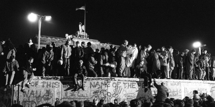 Einen Tag nach der Grenzöffnung feiern tausende Menschen aus Ost- und Westdeutschland gemeinsam auf, vor und hinter der Berliner Mauer am Brandenburger Tor.<address>© Eberhard Klöppel / dpa</address>