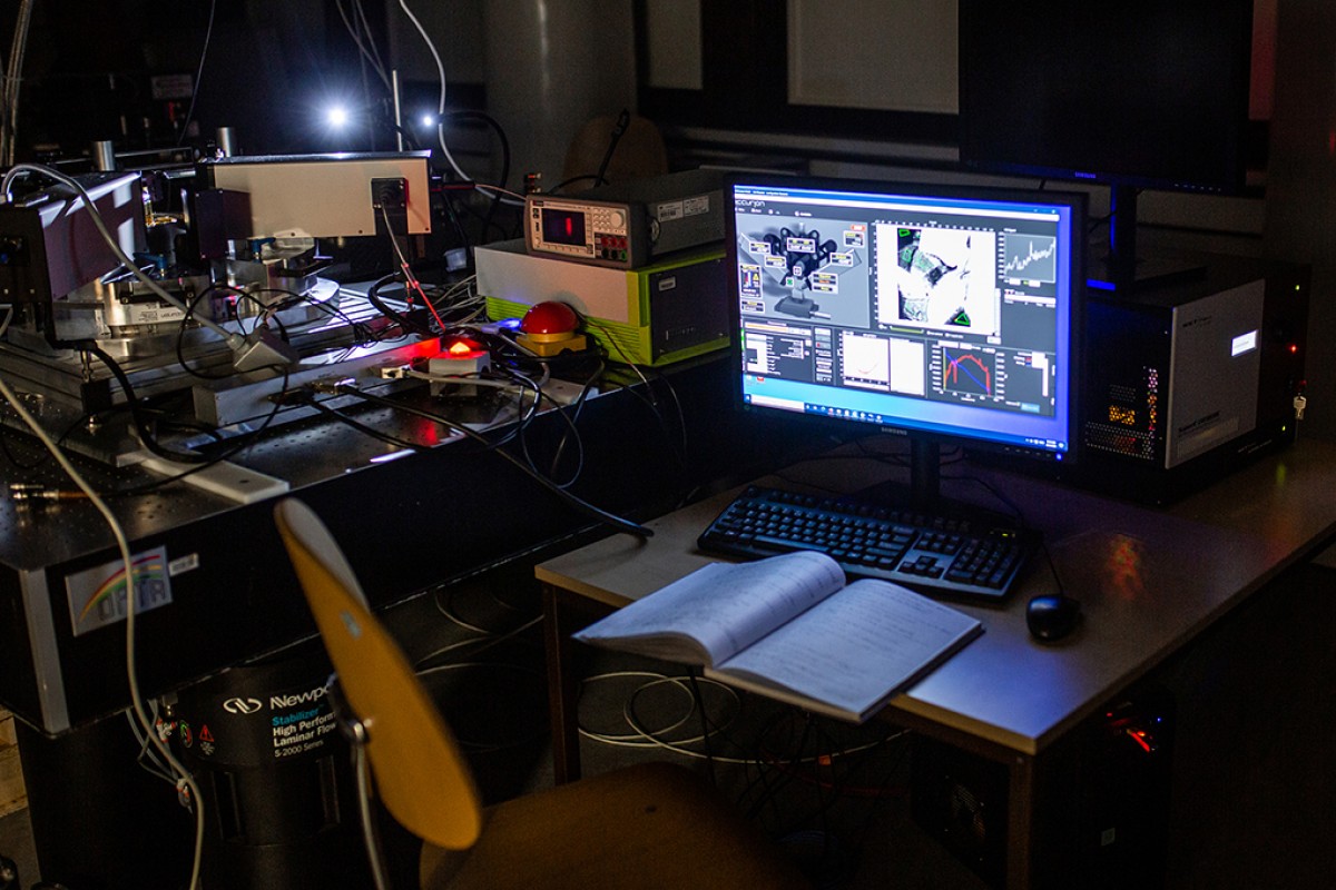 Über eine Laserapparatur können die Forscher Lichtpulse auf die Probe geben. Über einem Monitor kontrollieren sie das Experiment und verfolgen die Messdaten. © WWU - Peter Leßmann