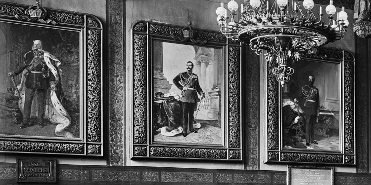 Das nach 1918 entstandene Foto zeigt Porträts der drei Hohenzollernkaiser, die in der Aula des alten Hauptgebäudes der WWU hingen.<address>© LWL-DLBW</address>