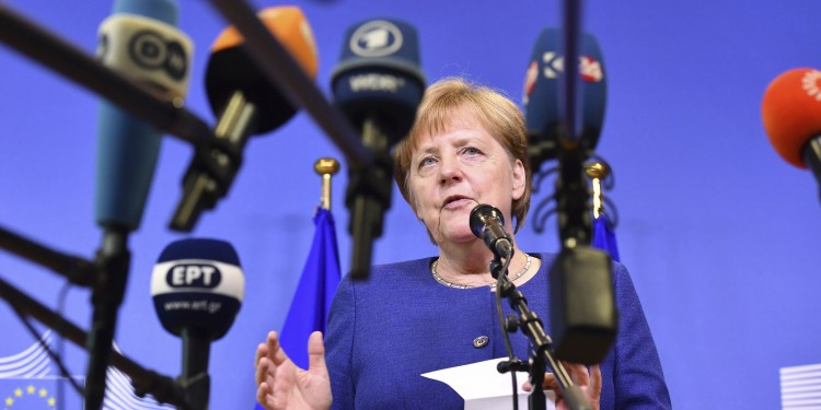Auf dem Foto sieht man Angela Merkel umringt von vielen Mikrophonen, die das Logo von Rundfunksendern tragen.<address>© picture alliance/AP Photo | Geert Vanden Wijngaert</address>