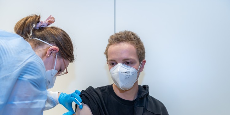 Eine Medizinstudentin impft einen Kommilitonen. Die Impfaktion der WWU richtet sich morgen (Mittwoch) an alle, deren Erstimmunisierung mindestens drei Monate zurückliegt.<address>© WWU - Michael Moeller</address>