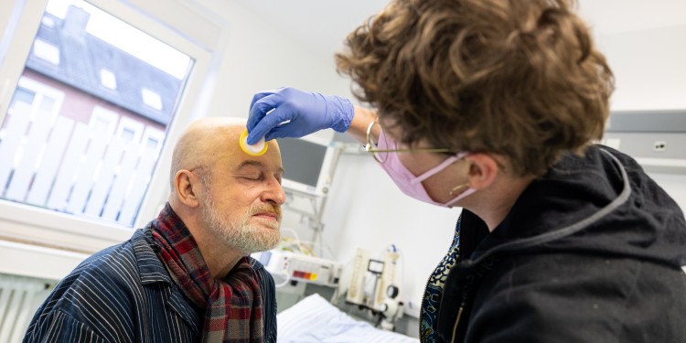 Das gelbe Puder, das Theaterpädagogin Julia Browne aufträgt, macht Michaels simulierte Leberzirrhose für die Studierenden noch realistischer.<address>© WWU - Peter Leßmann</address>