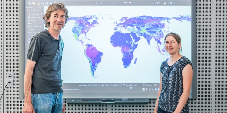 Prof. Dr. Edzer Pebesma und Prof. Dr. Hanna Meyer diskutieren die verschiedenen Variablen und Indikatoren auf einer digitalen globalen Umweltkarte.<address>© WWU - Michael Möller</address>