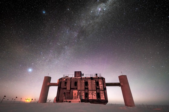 Front view of the IceCube Lab at twilight, with a starry sky showing a glimpse of the Milky Way overhead and sunlight lingering on the horizon.<address>© Martin Wolf, IceCube/NSF</address>