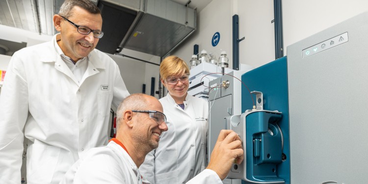 Prof. Hans-Ulrich Humpf, Dr. Benedikt Cramer and PhD student Amelie Frank at the new spectrometer (from left). The team can use this piece of equipment to demonstrate the presence of small quantities of mycotoxins and other substances.<address>© Münster University - Peter Leßmann</address>
