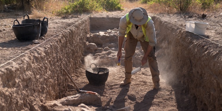 Dusty work: in temperatures of around 40 degrees, a student cleans one part of the excavation field.<address>© WWU - Sophie Pieper</address>