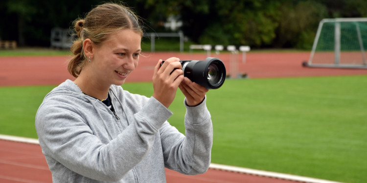 Wichtiges Arbeitsmittel: Für Social-Media-Beiträge ist Paula Mertens viel mit der Kamera auf dem Sport-Campus unterwegs.<address>© Uni MS - Julia Harth</address>