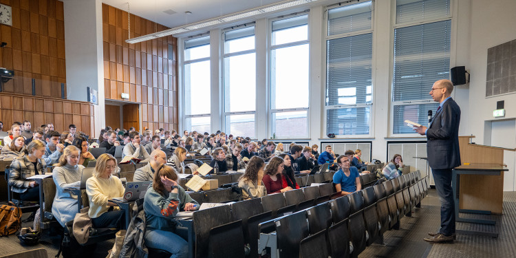 Der Dozent Sebastian Lohsse steht auf einem kleinen Podest und spricht zu den Studierenden im Hörsaal.<address>© Uni MS - Johannes Wulf</address>