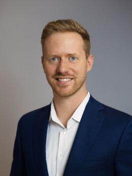 Zu sehen ist ein Porträtfoto von Dr. Pascal Büsing vor grauem neutralen Hintergrund.<address>&copy; privat</address>