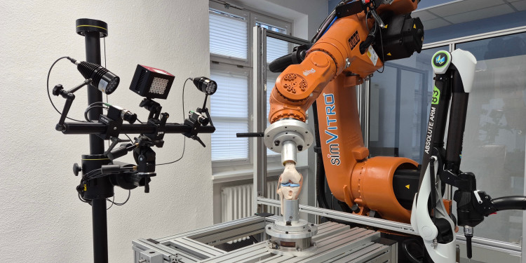 Das Bild zeigt einen orangenen Roboterarm. An dem Roboterarm ist ein Kniegelenk befestigt.<address>© Matthias Klimek</address>