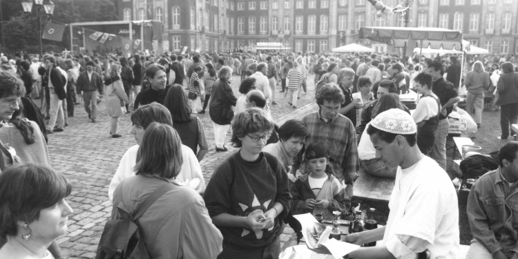 Die Schwarz-weiß-Aufnahme zeigt zahlreiche Menschen auf dem Schlossplatz. Entlang des gepflasterten Hauptwegs zum Schloss befinden sich einige Büfettstände, an denen Menschen anstehen.<address>© LWL-Medienzentrum für Westfalen, Bildarchiv</address>