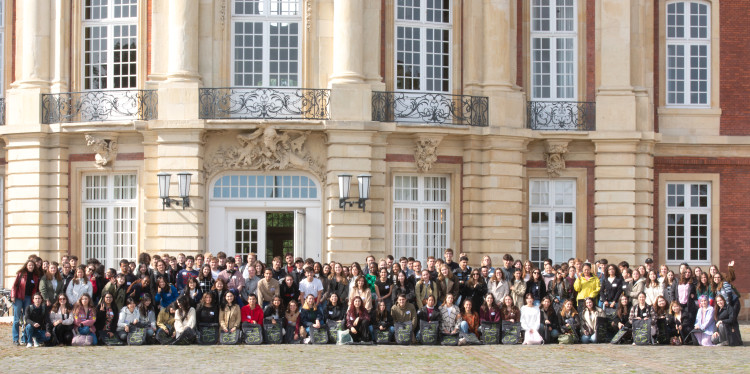 Zu sehen ist eine große Gruppe internationaler Studierender vor dem Haupteingang des Schlosses.<address>© Uni MS – Brigitte Heeke</address>