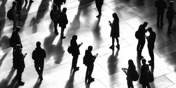 Zu sehen ist ein belebter Platz mit vielen Menschen, von denen viele auf ihr Handy schauen. Die abgebildeten Menschen sind nur als Silhoutten vor einem hellen Hintergrund zu erkennen.<address>© Adobe - Andres Mejia</address>