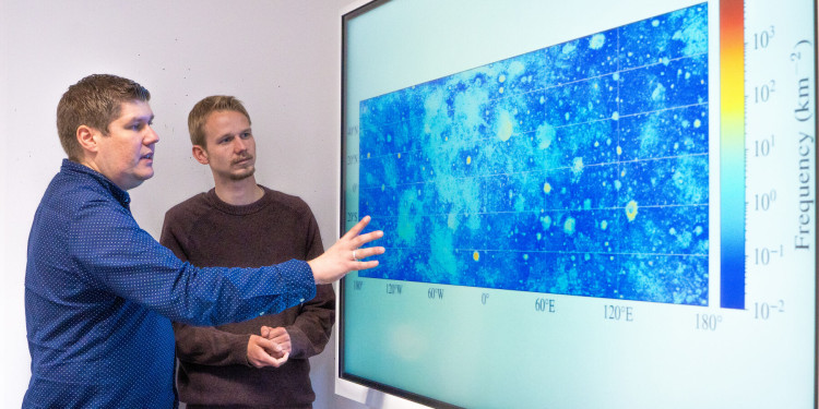 Prof. Bastian Gundlach and doctoral student Ben Aussel (from left) look at the map of the moon’s surface which shows around 94 million boulders.<address>© Uni MS - Linus Peikenkamp</address>