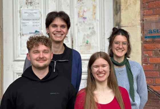 Zwei Mäner und zwei Frauen, die Vorsitzenden des AStA, stehen vor dem Eingang des AStA-Häuschens und schauen in die Kamera.<address>© privat</address>