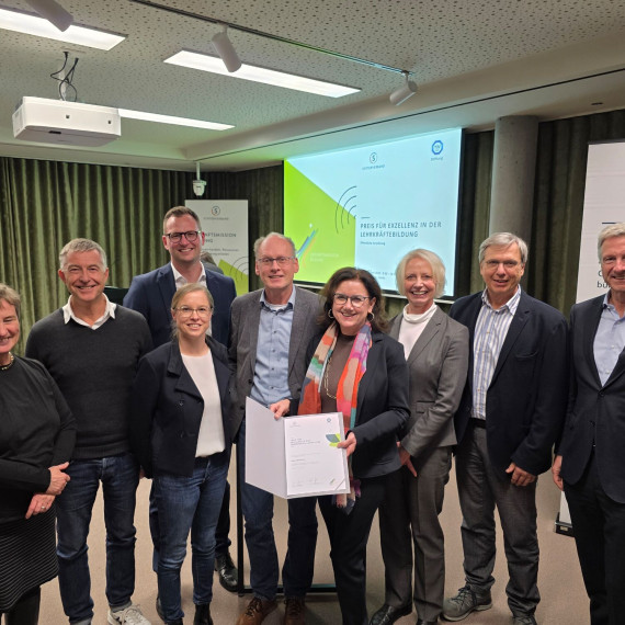 Das Bild zeigt das Siegerteam der Universität Münster. Insgesamt sind neun Personen zu sehen. In der Mitte steht Prof. Dr. Ulrike Weyland, Prorektorin für Studium und Lehre, und präsentiert die Siegerurkunde.<address>© Uni MS - Norbert Robers</address>