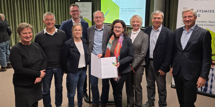 Das Bild zeigt das Siegerteam der Universität Münster. Insgesamt sind neun Personen zu sehen. In der Mitte steht Prof. Dr. Ulrike Weyland, Prorektorin für Studium und Lehre, und präsentiert die Siegerurkunde.<address>© Uni MS - Norbert Robers</address>