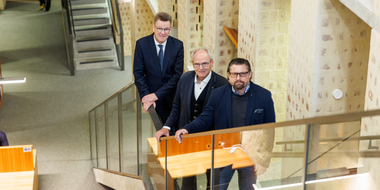 Rektor Prof. Dr. Johannes Wessels (l.) gratuliert ezur Millionen-Förderung: Prof. Hubert Wolf (Mitte) und Prof. Dr. Patrick Sänger freuen sich über die Unterstützung ihrer geisteswissenschaftlichen KI-Forschung durch die Akademienunion.<address>© Uni Münster - Peter Leßmann</address>