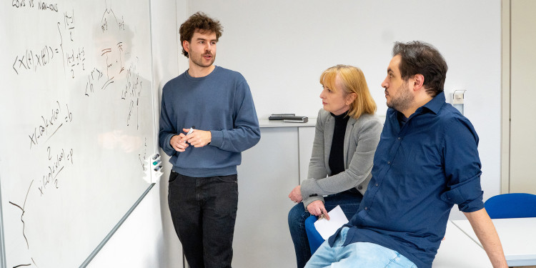 Dr. Johannes Pirsch, Prof Anna Kulesza and Dr. Domenico Bonocore (v. l.) in front of a whiteboard covered in formulas in a seminar room<address>© Uni MS - Linus Peikenkamp</address>
