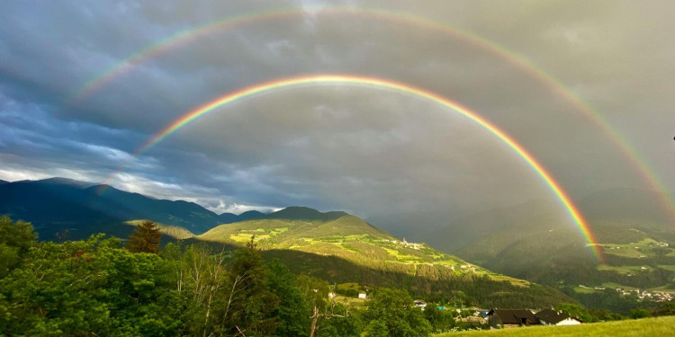 Ein doppelter Regenbogen über einer hügeligen Wiesenlandschaft vor teils wolkenverhangenem Himmel<address>© pexels.com - orlando s.</address>