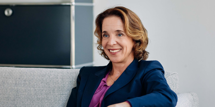 Porträt von Stephanie Coßmann, die auf einem Sofa sitzt und ihren Gesprächspartner anlächelt. Dieser ist jedoch nicht im Bild zu sehen.<address>&copy; Symrise</address>