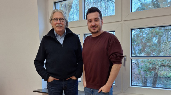 Prof. Dr. Norbert Sachser (links) und Dr. Niklas Kästner stehen vor einem Sprossenfenster, draußen sieht man unscharf Bäume<address>&copy; Uni MS - Christina Hoppenbrock</address>