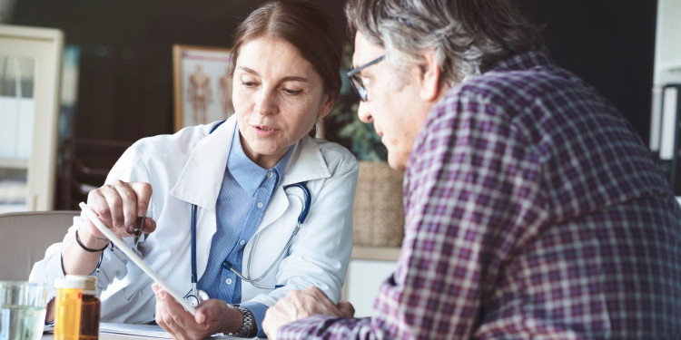 Auf dem Bild ist eine Ärztin im Gespräch mit einem älteren Patienten zu sehen.<address>&copy; stock.adobe.com - sebra</address>