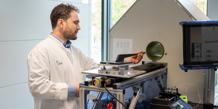 Philipp Backhaus steht im weißen Kittel an einem Positronen-Emissions-Tomographen.<address>&copy; Uni MS - Johannes Wulf</address>