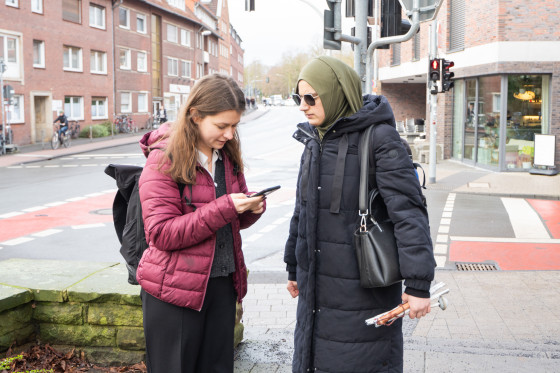 Damit Kübrnur Binek und Madita Laumen das benötigte Buch finden, schaut die Assistentin noch einmal auf dem Smartphone nach dem genauen Standort.<address>&copy; Uni MS - Linus Peikenkamp</address>