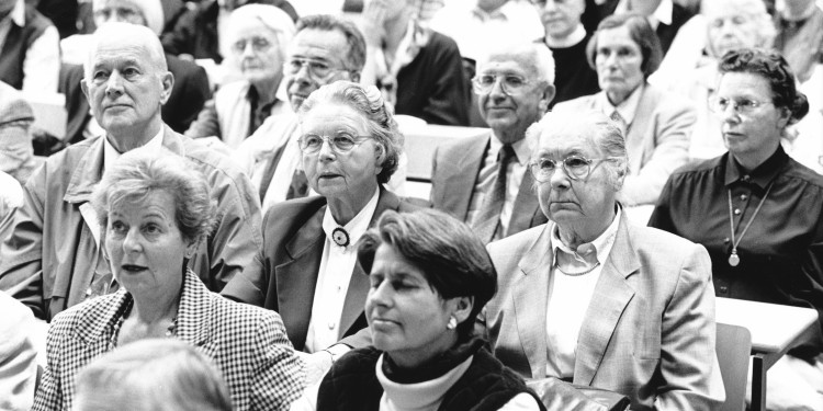 Das Schwarz-weiß-Foto zeigt mehrere Teilnehmerinnen und Teilnehmer des Studiums im Alter, die eine Vorlesung verfolgen.<address>&copy; Manfred Vollmer, Essen / Universität Münster</address>