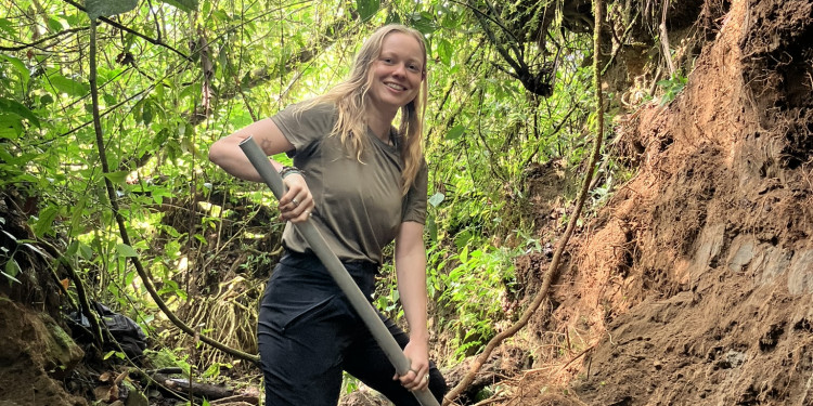 Das Bild zeigt Luca-Luisa Johannemann in Gummistiefeln mit Schaufel am Rand eines kleinen Flusses. Sie lächelt in die Kamera. Im Hintergrund ist der Regenwald zu sehen.<address>&copy; privat</address>