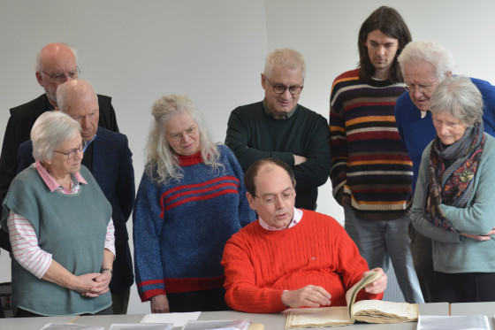Pictured are several members of the research team led by musicologist Daniel Glowotz (centre). In front of them on the table are several archival documents.<address>&copy; University of Münster - Brigitte Heeke</address>