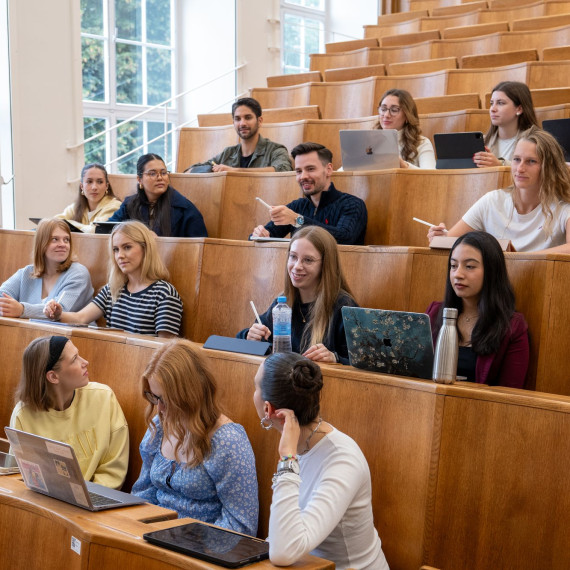 Das Bild zeigt einen Vorlesungssaal mit Holzbänken in denen junge Frauen und Männer sitzen.<address>&copy; Uni MS - Johannes Wulf</address>