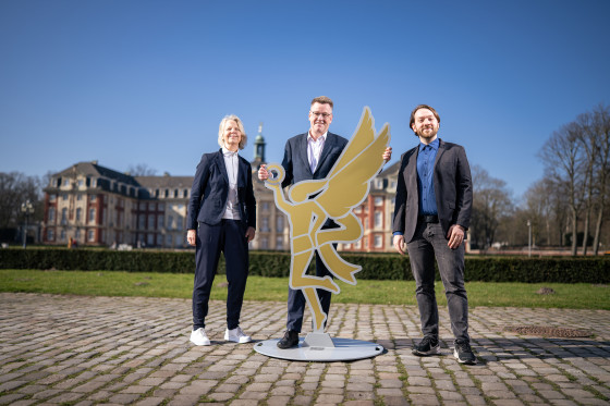 Auf dem Foto stehen drei Personen mit der Nike vor dem Schloss in Münster.<address>&copy; Uni MS - Thomas Mohn</address>