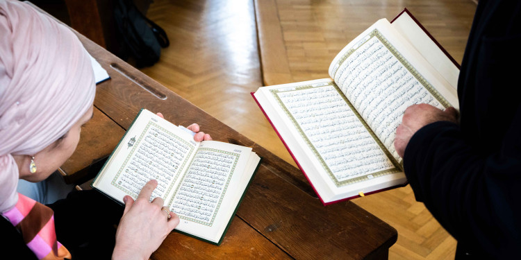 Zwei Personen halten jeweils einen Koran. Die Personen sind nur am Rande zu erkennen, die Bücher sind in der Mitte zu sehen.<address>&copy; Uni MS - Linus Peikenkamp</address>