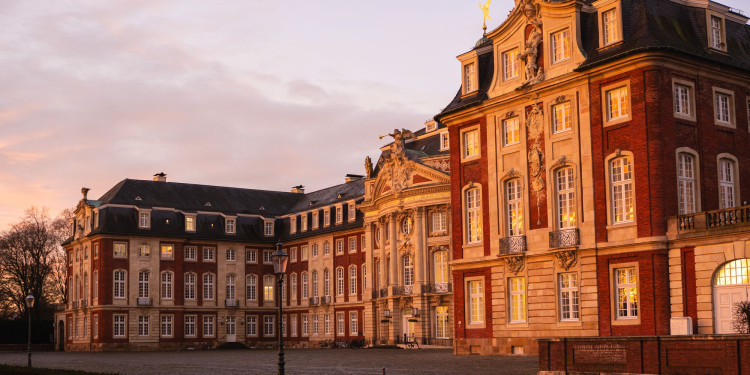 Auf dem Symbolbild ist das Schloss als Sitz der Universitätsverwaltung im Abendlicht zu sehen.<address>&copy; Uni MS - Linus Peikenkamp</address>