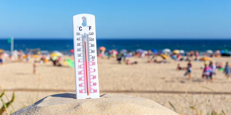 Auf dem Foto ist ein Thermometer zu sehen und im Hintergrund Strand und Meer.<address>&copy; stock.adobe.com - Sergo</address>