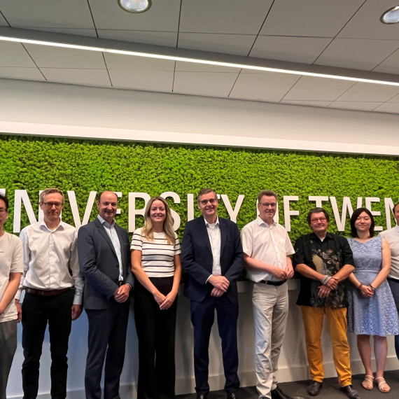 A group photo of nine people standing in front of the ‘University of Twente’ sign.<address>&copy; University of Twente</address>