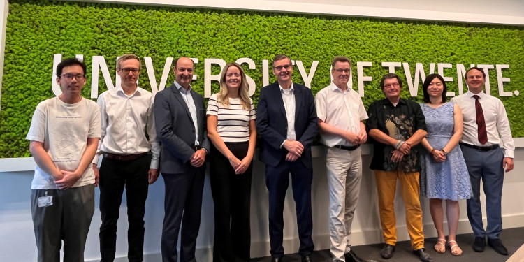 A group photo of nine people standing in front of the ‘University of Twente’ sign.<address>&copy; University of Twente</address>
