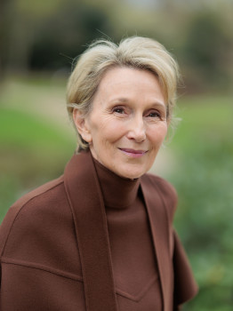 A head-and-shoulders portrait of a smiling woman, taken outdoors (a hedge and trees can be seen out of focus in the background).<address>&copy; Uni MS - MünsterView</address>