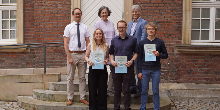Sechs Personen stehen für ein Gruppenfoto zusammen: Vorne (v. l.) die ausgezeichneten Absolventen Luca-Luisa Johannemann, Johannes Lier und Jannes Nauert - dahinter stehen Prof. Dr. Benjamin Bomfleur, Dr. Patricia Göbel und Prorektor Prof. Dr. Michael Quante.<address>&copy; Uni MS - K. Kottke</address>