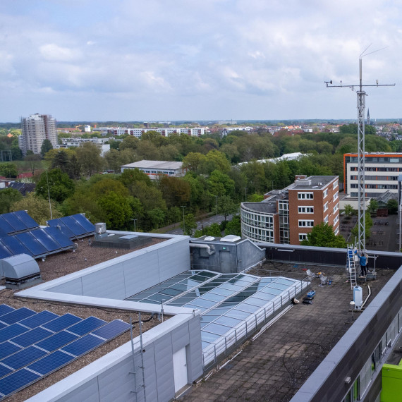 Aerial view of the GEO1 building, with the measurement tower rising several metres above one side of it. The skyline of the city of Münster can be seen in the background.<address>&copy; Uni MS - Johannes Wulf</address>