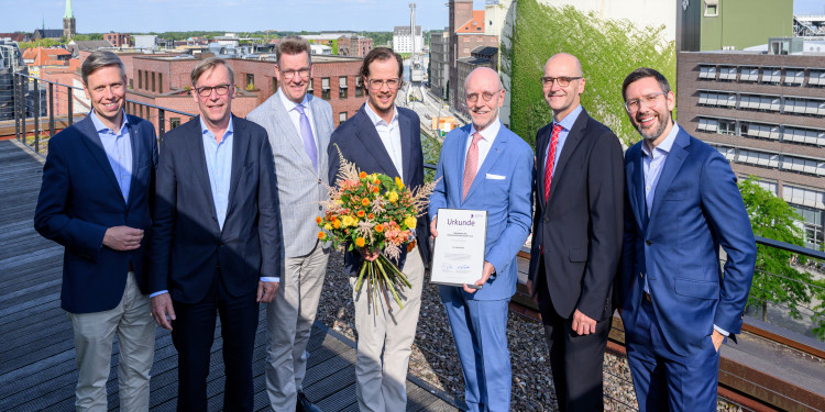 Das Foto zeigt eine Gruppe von Menschen, die in die Kamera gucken. In der Bildmitte steht Preisträger Dr. Colin Schulz.<address>&copy; Universitätsgesellschaft Münster - Michael Möller</address>