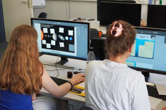 Das Foto ist ein Blick über die Schulter von zwei Studentinnen. Man sieht die Studentinnen von hinten und die Oberfläche der Monitore, an denen sie arbeiten.<address>&copy; Uni MS - Julia Harth</address>