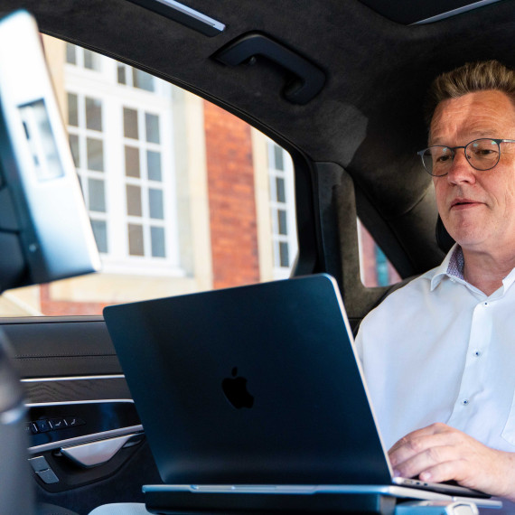 Das Bild zeigt den Rektor beim Arbeiten am Laptop in seinem Dienstwagen.<address>&copy; Uni MS - Linus Peikenkamp</address>