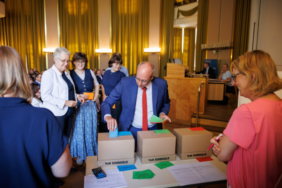 Das Bild zeigt die drei Wahlurnen und wie Mitglieder der Hochschulwahlversammlung ihre Stimme abgeben.<address>&copy; Uni MS - Peter Leßmann</address>